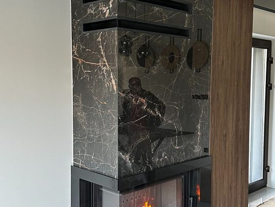 Nowoczesny kominek wykończony spiekien, kamieniem i drewnem