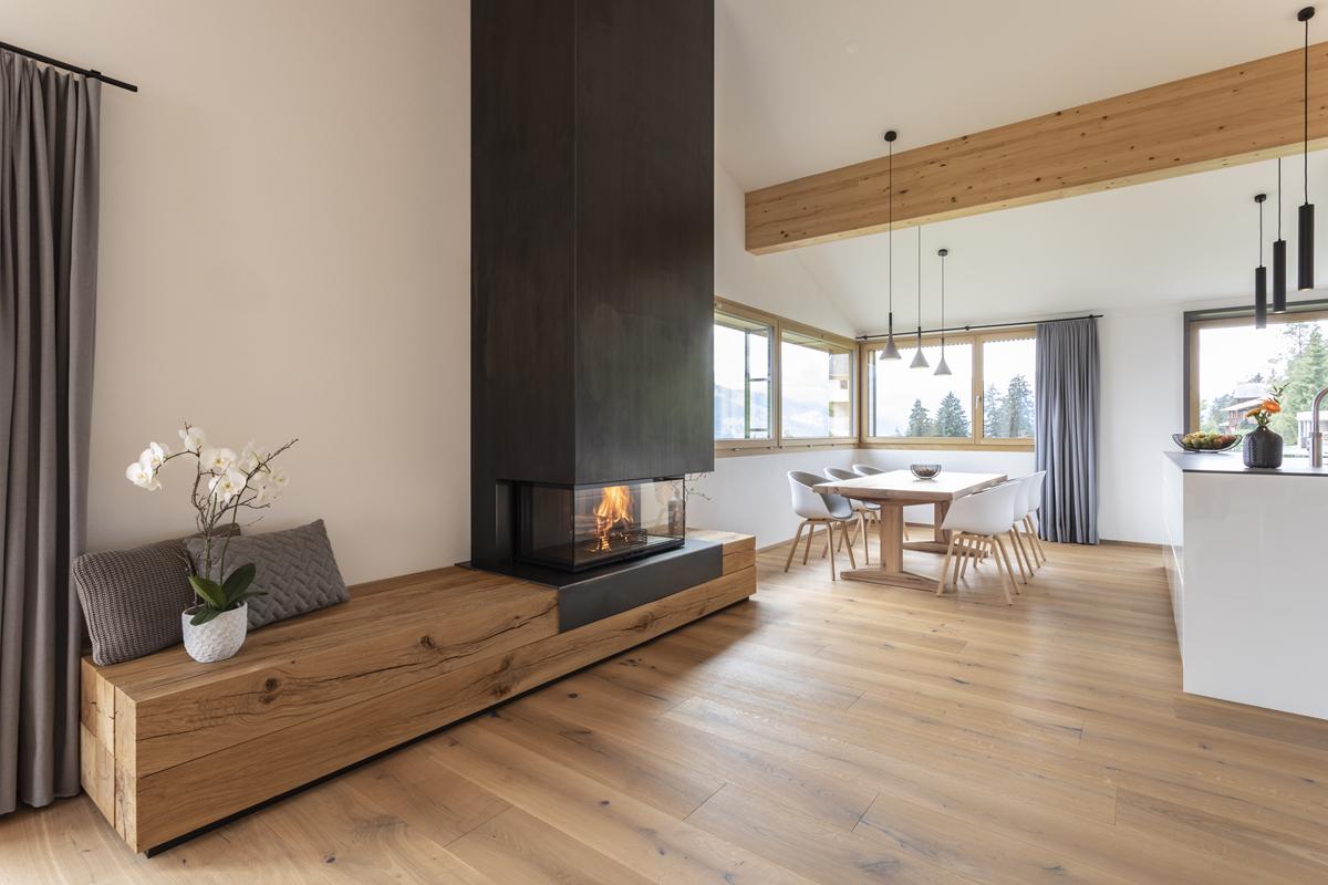 aranżacja kominka we wnętrzu, kominek wykończony czarną stalą z surowym balem drewna jako podstawą 